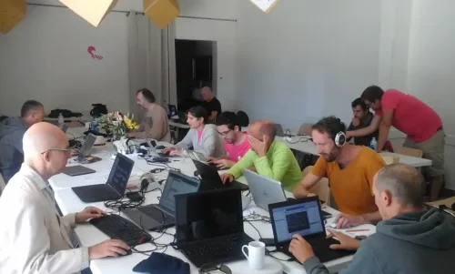 Ambiance studieuse, des personnes en train de coder sur leurs portables autour d'une grande table