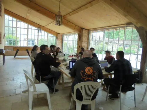 Ambiance studieuse, des personnes en train de coder sur leurs portables autour d'une grande table