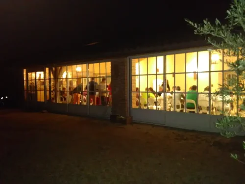 Ambiance nocturne, photo depuis l'extérieur d'un grand batiment, la nuit, où on voit à travers les portes fenêtres des personnes en train de coder