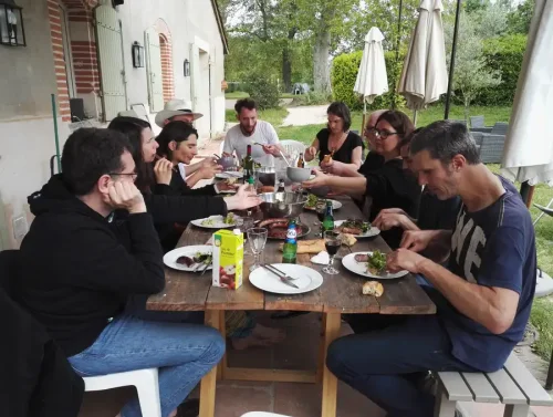 Des personnes en train de manger autour d'une grande table, en extérieur